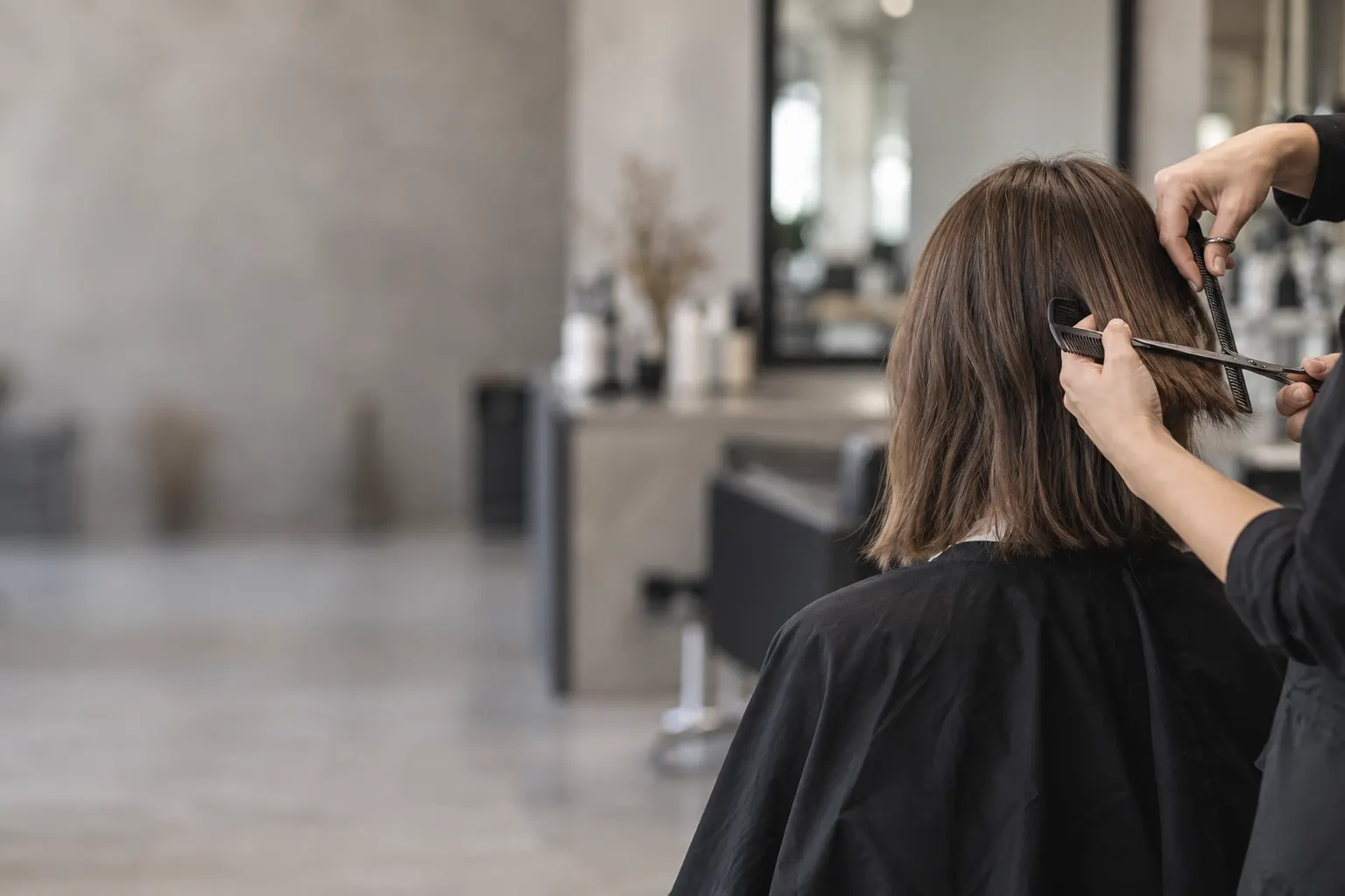 A hairdresser trims a client’s hair in a salon